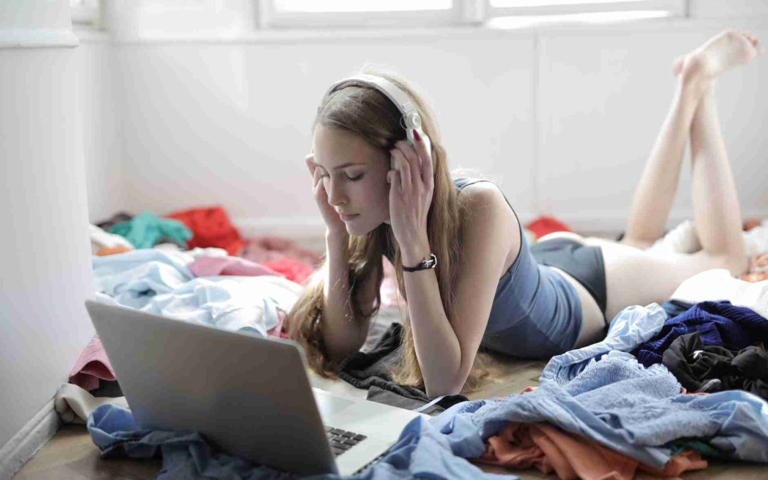 young woman watching movie in headphones in messy room